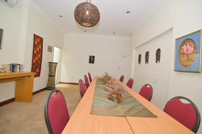 a conference room with a wooden table and red chairs at The Hellens Guest House in Pretoria