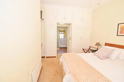 a white bedroom with a bed and a hallway at The Hellens Guest House in Pretoria