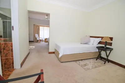 a bedroom with a bed and a table in a room at The Hellens Guest House in Pretoria