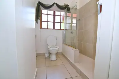 a bathroom with a toilet and a window at The Hellens Guest House in Pretoria