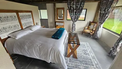 a bedroom with a bed and a chair and a window at Die Pekanneut in Polokwane