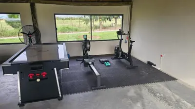 a gym with three treadmills and a table in a room at Die Pekanneut in Polokwane