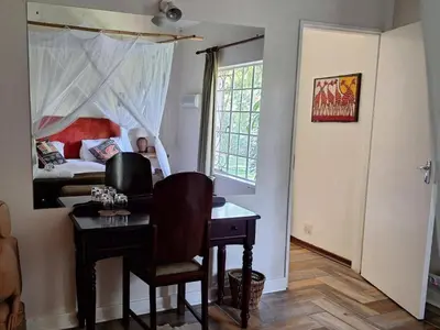 a room with a desk and a bedroom with a bed at Seringa Lodge & Safaris in White River