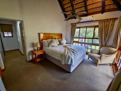 a bedroom with a bed and a chair and a window at Kruger Park Lodge 243 in Hazyview
