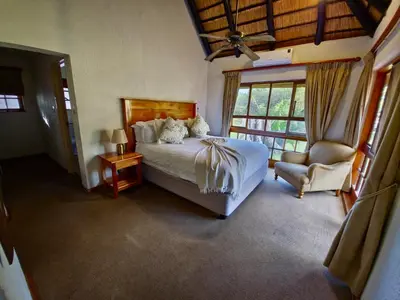 a bedroom with a bed and a chair and a window at Kruger Park Lodge 243 in Hazyview