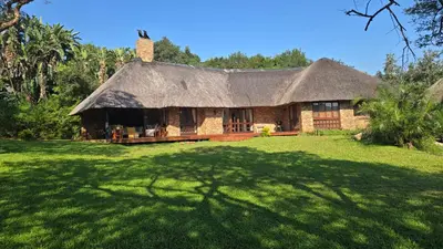 a house with a thatched roof on a grass field at Kruger Park Lodge 243 in Hazyview