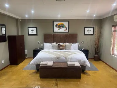 a large bedroom with a large bed and a couch at Mountain Dew Quest House in Noordkaap