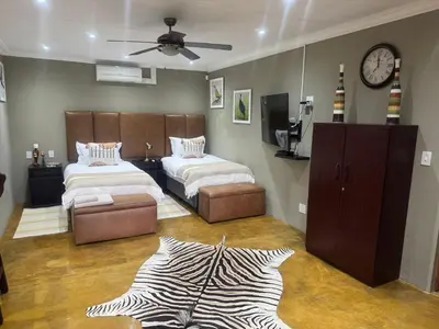 a bedroom with two beds and a zebra print rug at Mountain Dew Quest House in Noordkaap