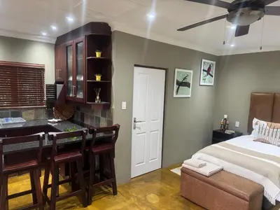 a bedroom with a bed and a kitchen with a desk at Mountain Dew Quest House in Noordkaap