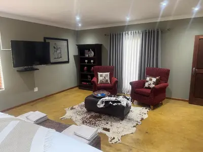 a living room with two chairs and a tv at Mountain Dew Quest House in Noordkaap