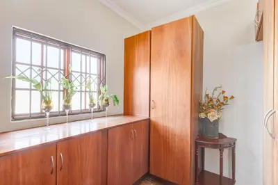 a room with wooden cabinets and a window with potted plants at Aaybee Recreational Home in Midrand