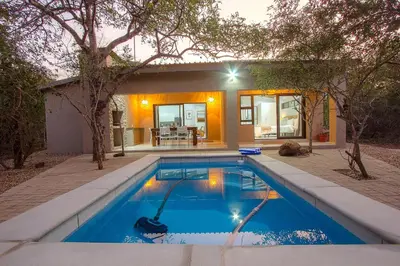 a swimming pool in front of a house at The Bush House Kruger in Marloth Park