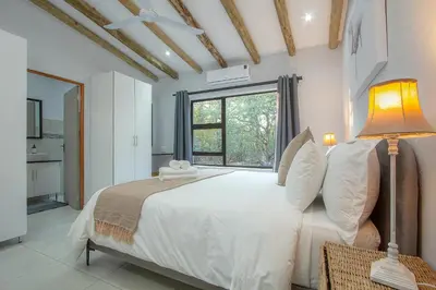 a bedroom with a large white bed and a window at The Bush House Kruger in Marloth Park