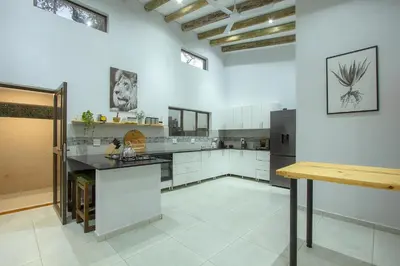 a large kitchen with white cabinets and a black counter at The Bush House Kruger in Marloth Park