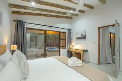 a bedroom with a large white bed and a desk at The Bush House Kruger in Marloth Park