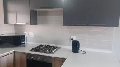 a kitchen with a stove and a microwave at Generous Apartment at Waterfall in Midrand