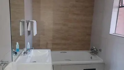 a bathroom with a white tub and a sink at Generous Apartment at Waterfall in Midrand