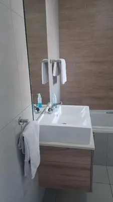 a bathroom with a sink and a mirror and a tub at Generous Apartment at Waterfall in Midrand