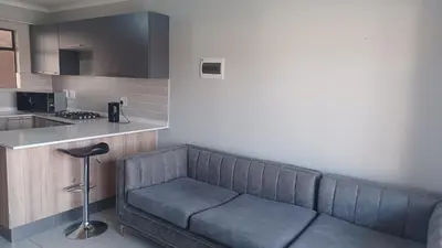 a living room with a couch in a kitchen at Generous Apartment at Waterfall in Midrand