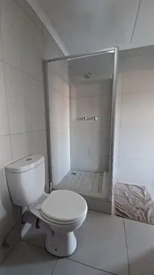 a white bathroom with a toilet and a shower at Generous Apartment at Waterfall in Midrand