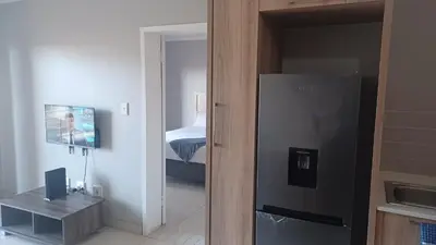 a room with a refrigerator and a bedroom with a bed at Generous Apartment at Waterfall in Midrand