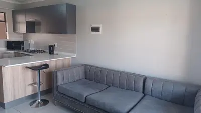 a living room with a couch in a kitchen at Generous Apartment at Waterfall in Midrand