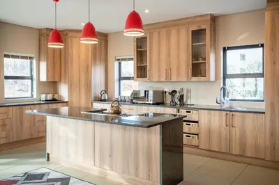 a kitchen with wooden cabinets and a large island at Highland Gate Golf & Trout Estate, House 910 in Dullstroom