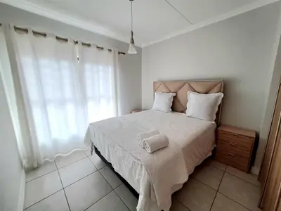 a bedroom with a large bed with white sheets and a window at The Blyde Crystal Lagoon in Pretoria