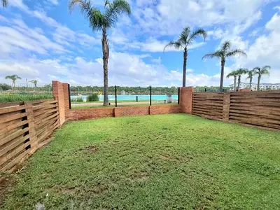 a backyard with a wooden fence and palm trees at The Blyde Crystal Lagoon in Pretoria
