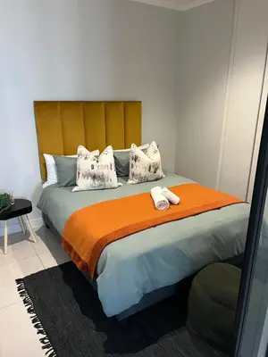a bedroom with a large bed with an orange blanket at 2411 Ellipse Waterfall in Midrand