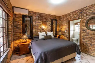 a bedroom with a bed and a brick wall at Mapula in Marloth Park