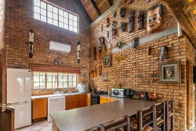 a kitchen with a brick wall and a refrigerator at Mapula in Marloth Park
