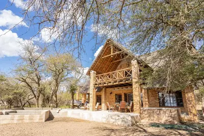 a stone house with a thatched roof at Mapula in Marloth Park