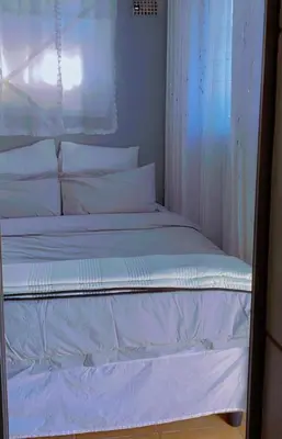 a bed with white sheets and pillows in a room at Holiday apartment in Kempton Park