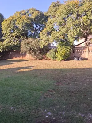 a large grass field with trees and a fence at Holiday apartment in Kempton Park