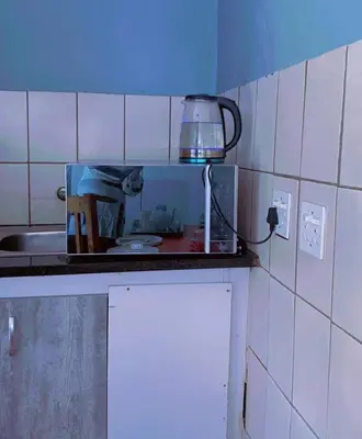 a kitchen counter with a microwave and a person in a kitchen at Holiday apartment in Kempton Park