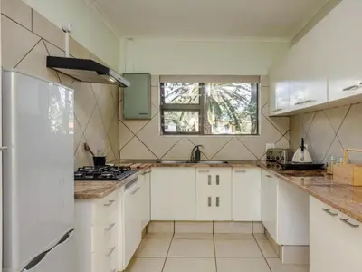 a kitchen with white cabinets and a window at Jacobs Well Guest House in Centurion