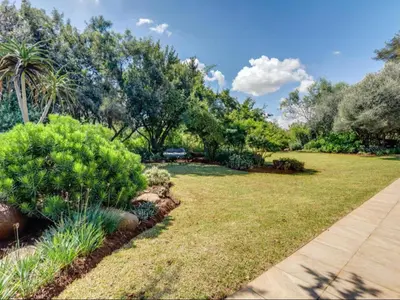 a garden with grass and bushes and trees at Jacobs Well Guest House in Centurion