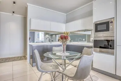 a kitchen with a glass table and some chairs at Luxurious living Waterfall in Midrand