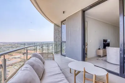 a living room with a couch and a balcony at Luxurious living Waterfall in Midrand