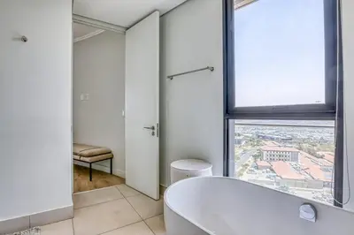 a white bathroom with a tub and a window at Luxurious living Waterfall in Midrand