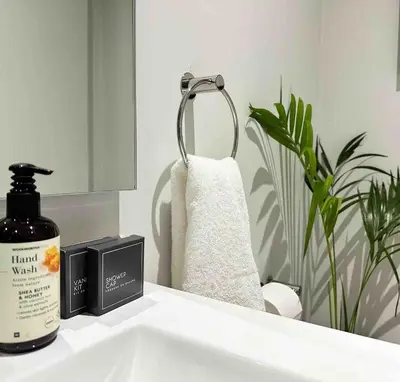 a bathroom sink with a bottle of hand moisturizing soap and a mirror at Explore Ellipse - Peacock Room in Midrand