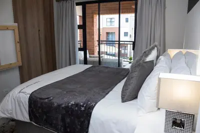 a bedroom with a bed with white sheets and a window at Serenity Stay at The Blyde River Walk Estate in Pretoria