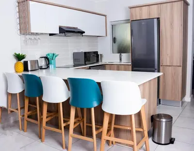 a kitchen with a white counter and blue chairs at Serenity Stay at The Blyde River Walk Estate in Pretoria