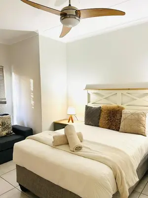 a bedroom with a large bed with a ceiling fan at Serenity Stay at The Blyde River Walk Estate in Pretoria