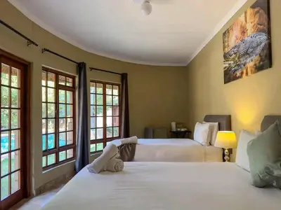 two beds in a room with two windows at 63OnNyala Function lodge and spa venue in Pretoria