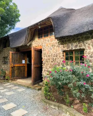 a stone house with a thatched roof and flowers at 63OnNyala Function lodge and spa venue in Pretoria