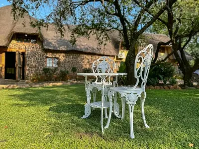 two white chairs and a table in front of a house at 63OnNyala Function lodge and spa venue in Pretoria