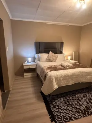 a bedroom with a bed and a night stand with two lamps at Haven on Glen in Johannesburg