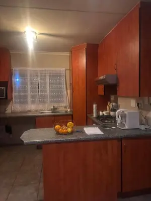 a kitchen with wooden cabinets and a bowl of fruit on a counter at Haven on Glen in Johannesburg